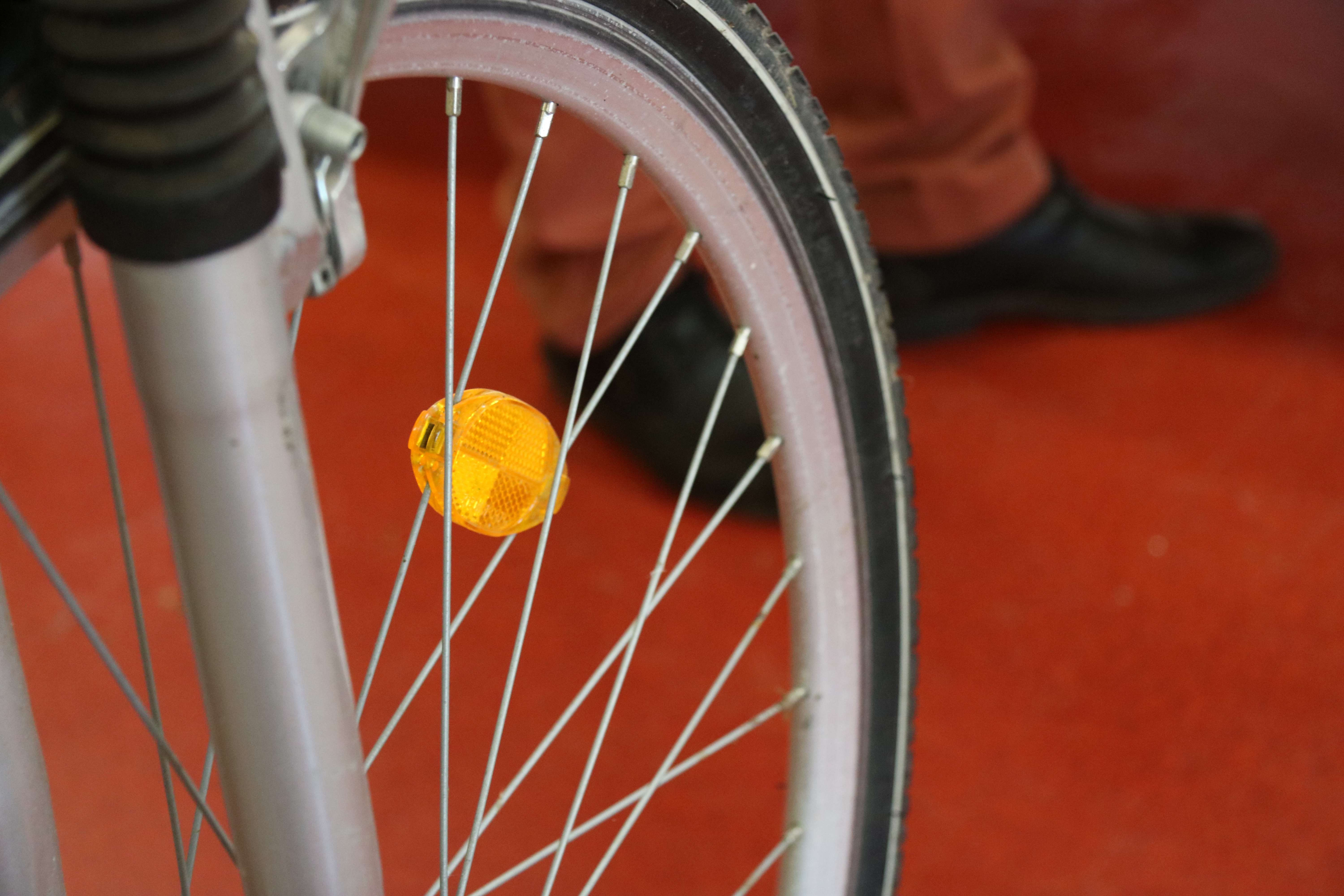 Das Speichenrad eines Fahrrades mit einem gelben Reflektor