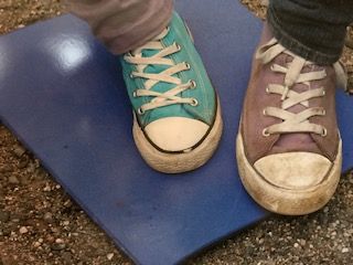 Zwei Füße in Schuhen stehen auf einer blauen Fliese. 